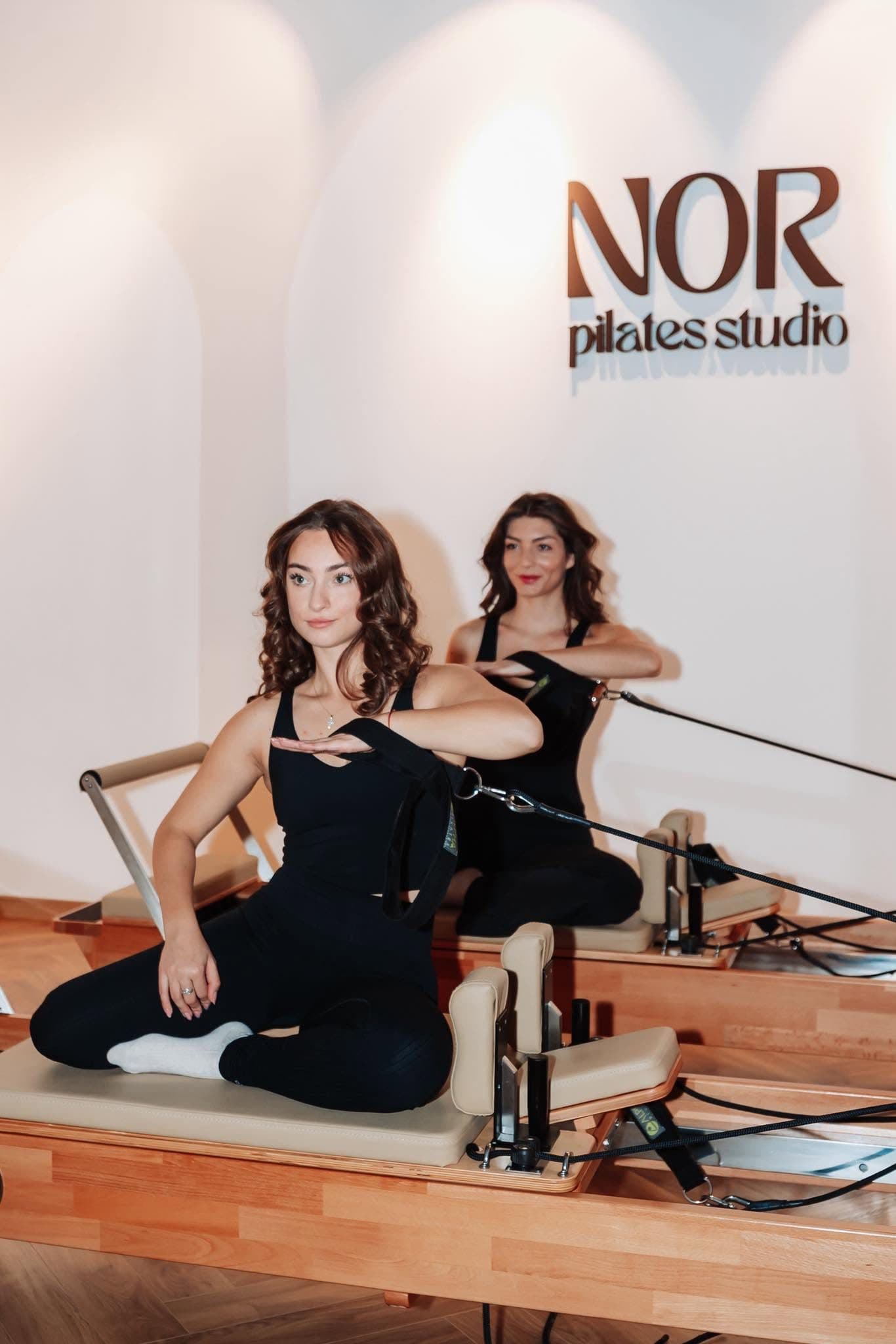 Clasă de pilates reformer cu logo-ul NOR pe perete